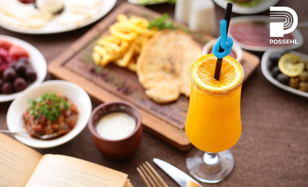 naranjada en copa con naranja sobre mesa con comida